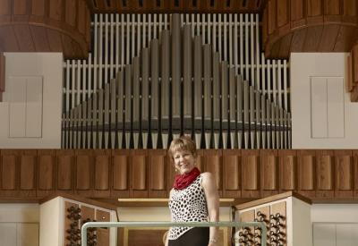 Faythe Freese, Concert Organist, standing in front of a pipe organ
