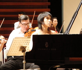 Yuja Wang rehearsing for the final tour concert; violinist/composer Mark Volkert is seen behind her 