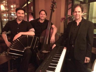 Three musicians: bandoneon player, bass player, pianist, all men, at night