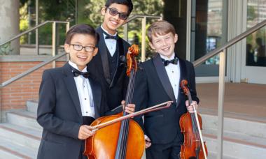 Colburn Community School string students smiling for a photo with their instruments.