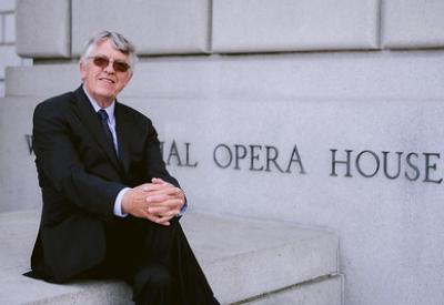 Ian Robertson wears a black suit, sitting outside of the War Memorial Opera House.