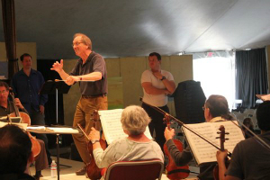 Festival co-founder and conductor Allan Pollack leads the Festival Orchestra through a rehearsal of "The Barber of Seville", with opera director and baritone Eugene Brancoveanu (in white t-shirt). (Photo by Jeff Kaliss)